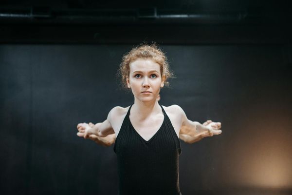 A calm and focused person starting a simple yoga pose indoors.
