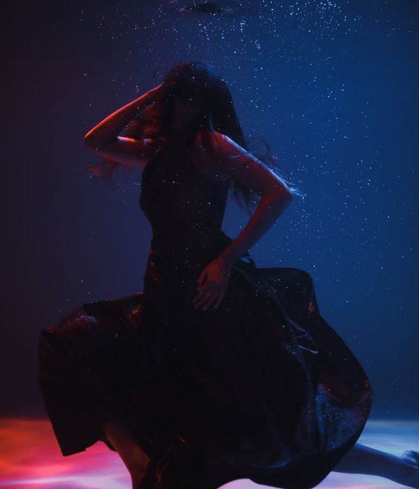 Woman in a dynamic yoga flow pose against a dark background with mint accents.